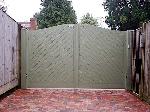 Green painted double wooden electric gatess